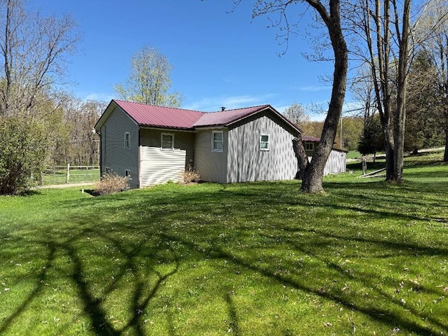 view of side of property with a yard, fence, and metal roof