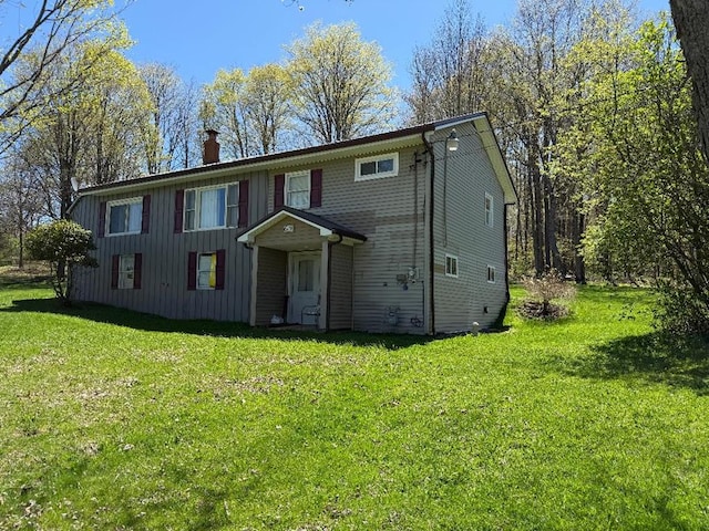 view of front of property featuring board and batten siding, a chimney, and a front lawn