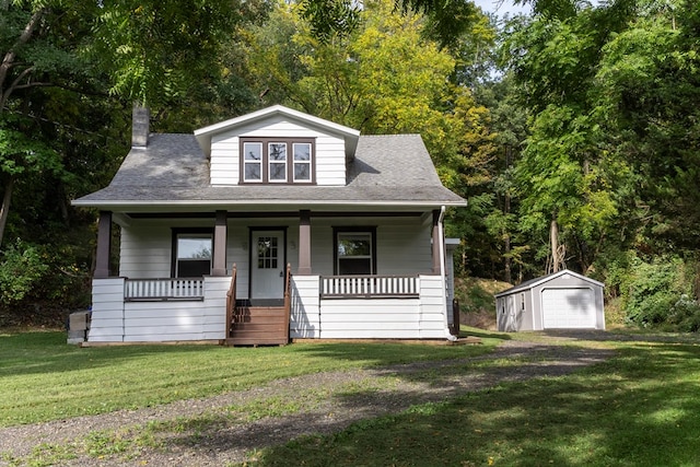 bungalow with covered porch, a garage, an outdoor structure, and a front lawn