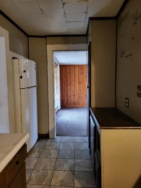 kitchen featuring white fridge and wood walls