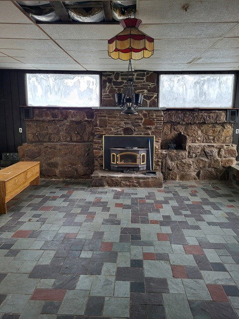 unfurnished living room with a paneled ceiling and a wood stove