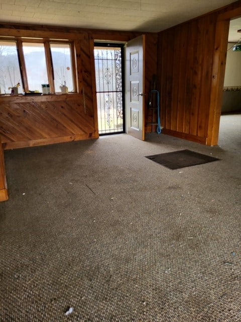 unfurnished living room with dark carpet and wooden walls