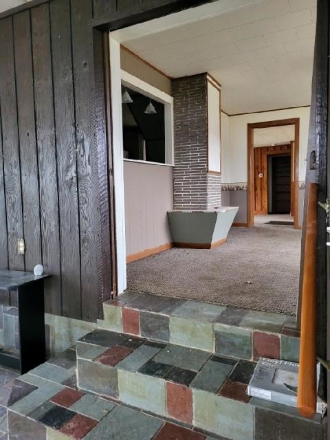 hallway featuring carpet flooring and wood walls