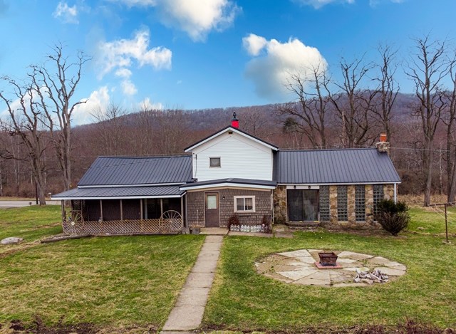 back of property with a yard, an outdoor fire pit, and a sunroom