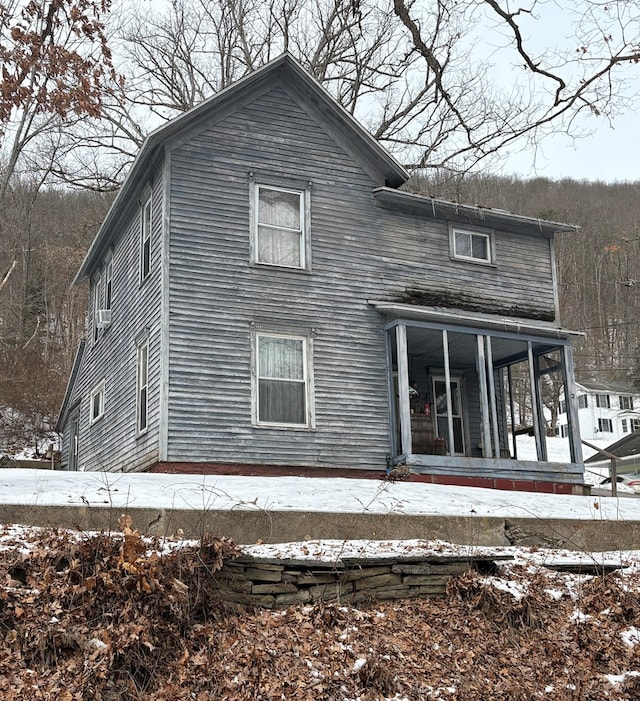 snow covered rear of property with a porch