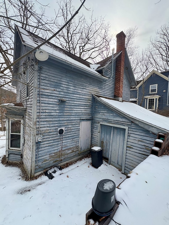 view of snow covered exterior with a chimney