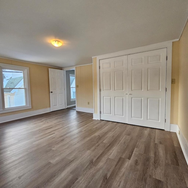 unfurnished bedroom with hardwood / wood-style flooring, crown molding, and a closet