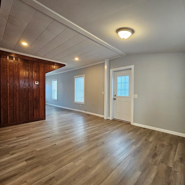 interior space featuring a wealth of natural light, wood-type flooring, and wooden walls