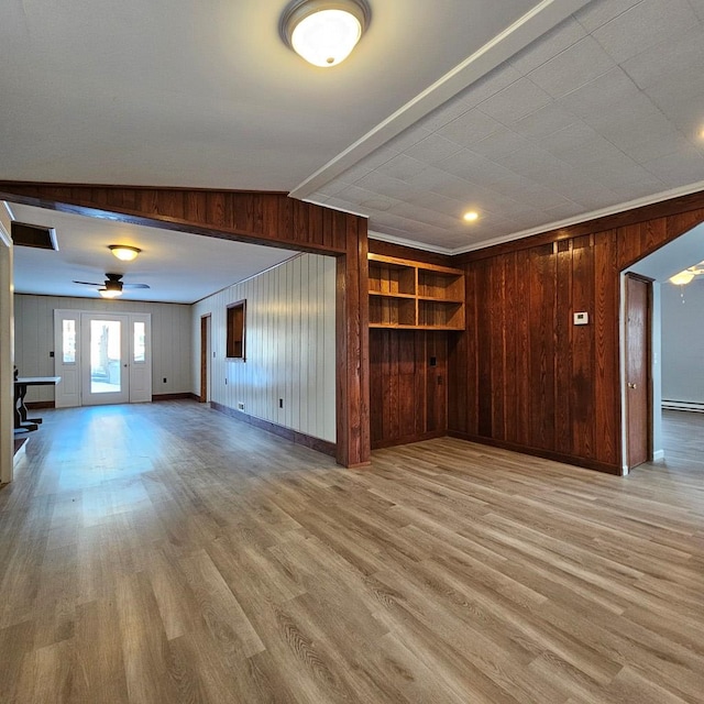 unfurnished living room with ceiling fan, ornamental molding, light hardwood / wood-style flooring, and wood walls