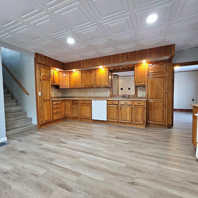 kitchen featuring white dishwasher, sink, and light wood-type flooring