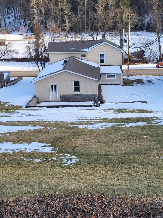 snow covered back of property with a yard