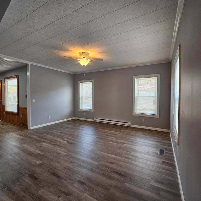 spare room with baseboard heating, a healthy amount of sunlight, ornamental molding, and dark hardwood / wood-style flooring