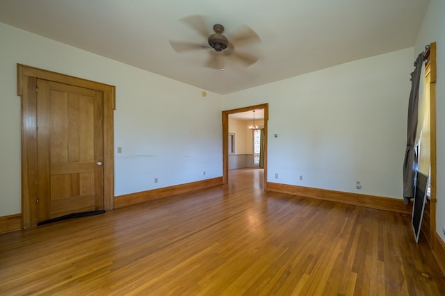 spare room with ceiling fan with notable chandelier and hardwood / wood-style flooring