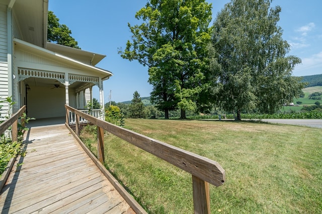 wooden deck featuring ceiling fan and a yard