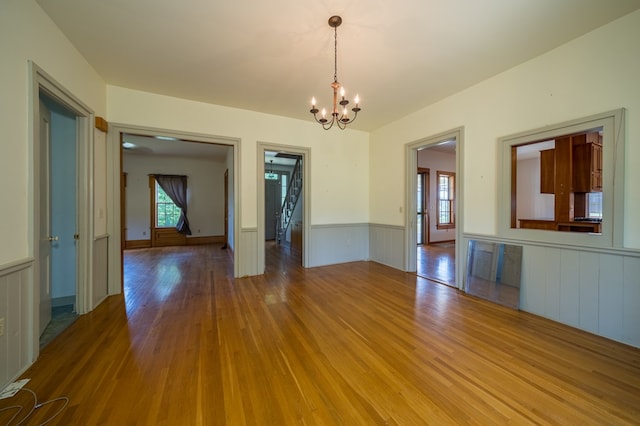 unfurnished dining area with hardwood / wood-style flooring, plenty of natural light, and a notable chandelier