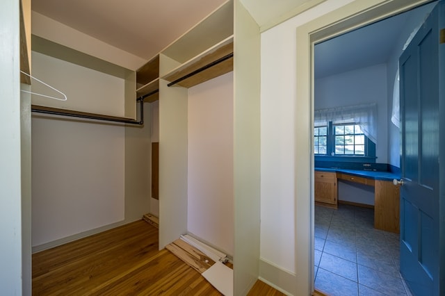 walk in closet featuring dark hardwood / wood-style flooring and built in desk