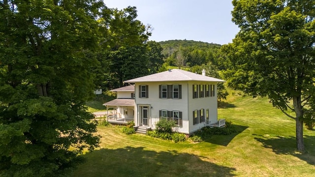 rear view of house featuring a porch and a lawn