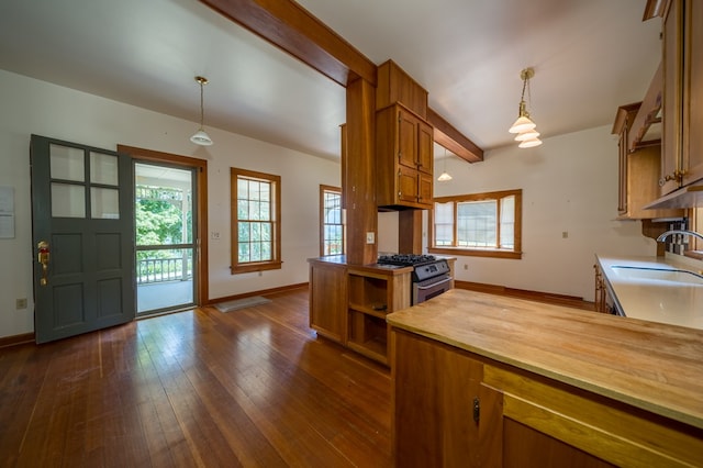 kitchen with wood counters, gas stove, sink, decorative light fixtures, and dark hardwood / wood-style floors