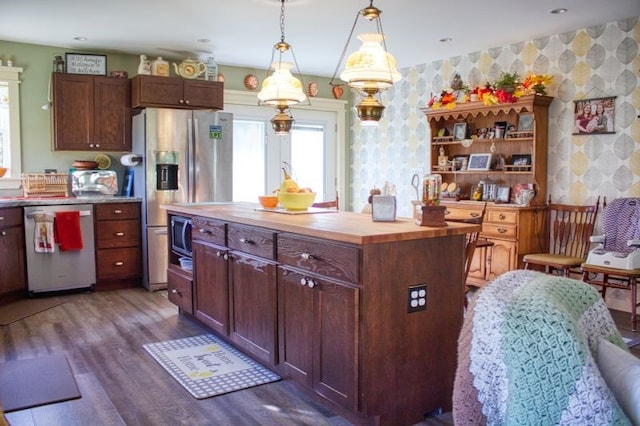 kitchen featuring wood counters, dark hardwood / wood-style flooring, stainless steel appliances, pendant lighting, and a center island