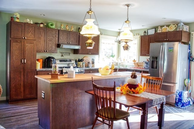 kitchen with hardwood / wood-style floors, decorative light fixtures, a kitchen island, and appliances with stainless steel finishes