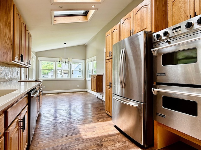 113 1st St, Shinglehouse, PA 16748 - kitchen with stainless steel appliances, wood finished floors, vaulted ceiling, a chandelier, and decorative backsplash