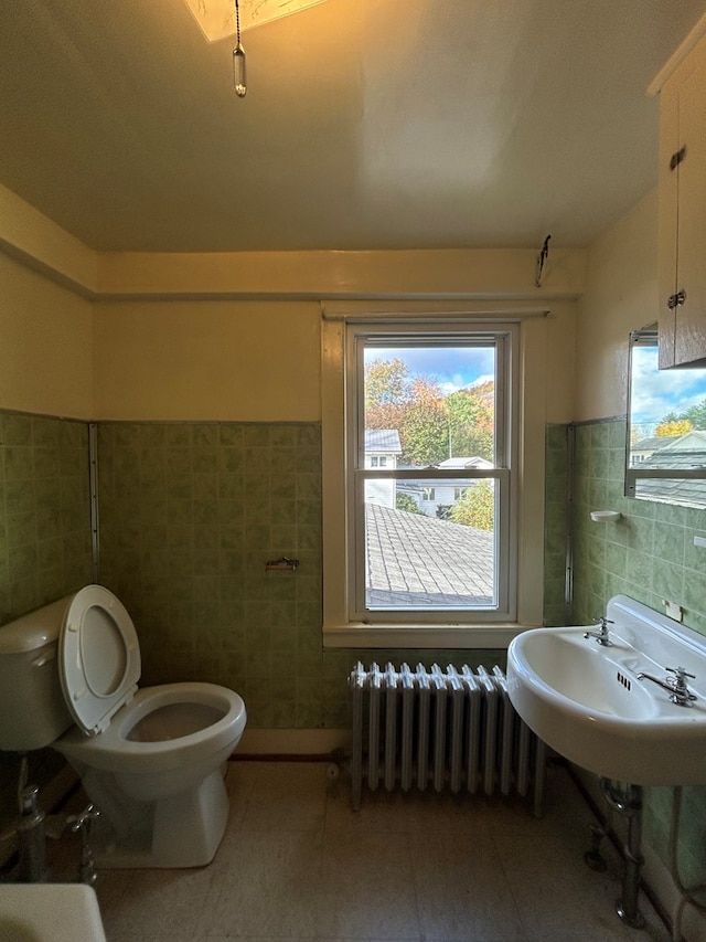 bathroom featuring sink, radiator heating unit, tile walls, and toilet