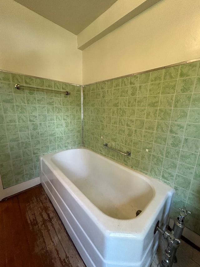 bathroom with a bathing tub, hardwood / wood-style floors, and tile walls