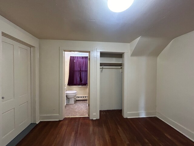 unfurnished bedroom with ensuite bath, dark hardwood / wood-style floors, and a baseboard heating unit