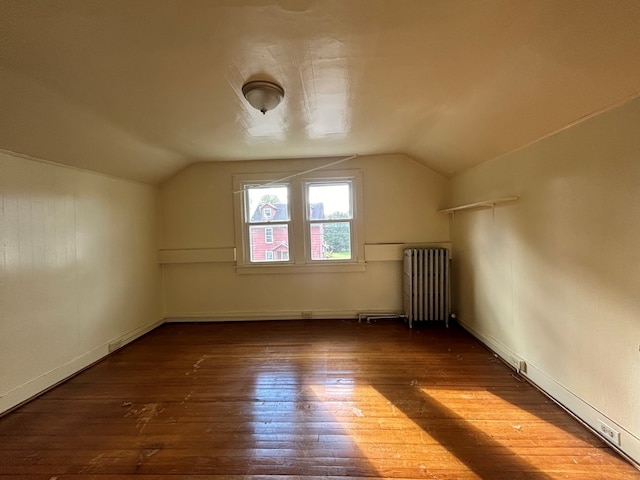 bonus room with dark hardwood / wood-style flooring, vaulted ceiling, and radiator