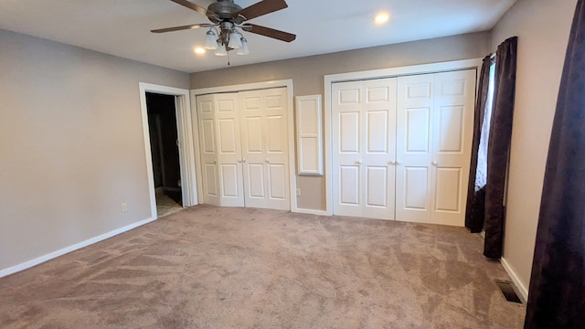 unfurnished bedroom with ceiling fan, carpet floors, and two closets