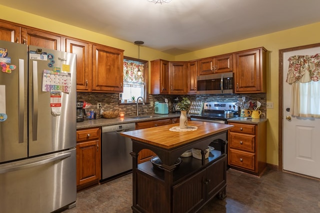 kitchen with a center island, hanging light fixtures, sink, appliances with stainless steel finishes, and tasteful backsplash