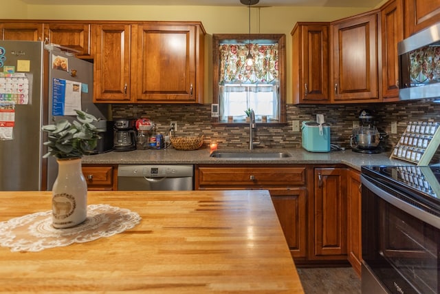 kitchen featuring pendant lighting, sink, appliances with stainless steel finishes, tasteful backsplash, and butcher block counters