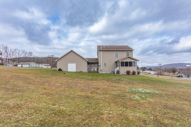 rear view of property featuring a sunroom, a mountain view, and a yard