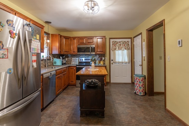 kitchen featuring sink, a center island, hanging light fixtures, stainless steel appliances, and wood counters