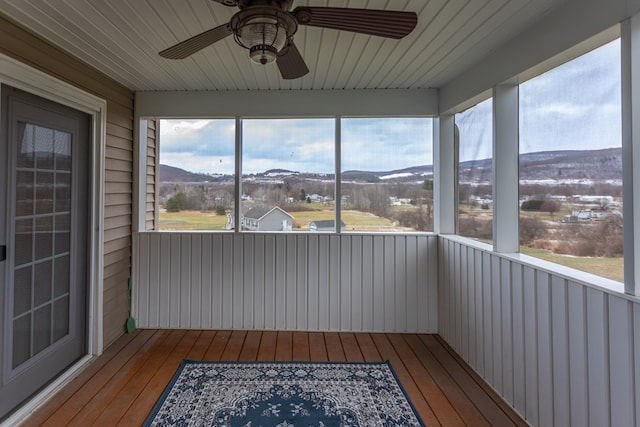 unfurnished sunroom featuring a mountain view, ceiling fan, and plenty of natural light