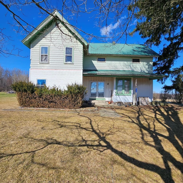 rear view of property featuring metal roof and a lawn