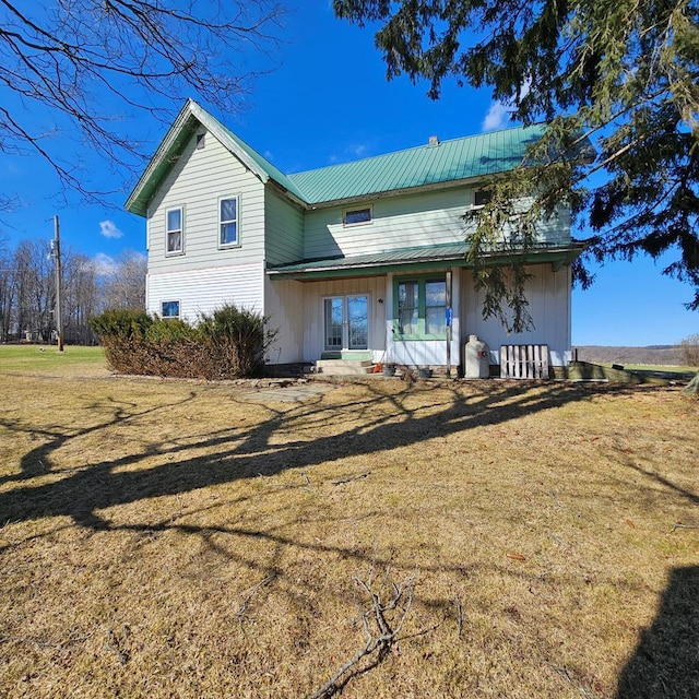 back of house featuring metal roof and a yard