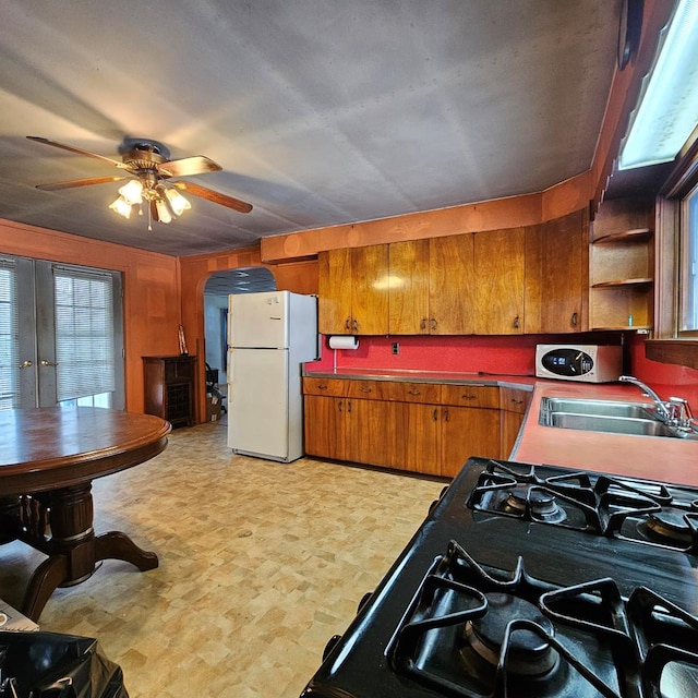 kitchen featuring gas stove, ceiling fan, sink, french doors, and white fridge