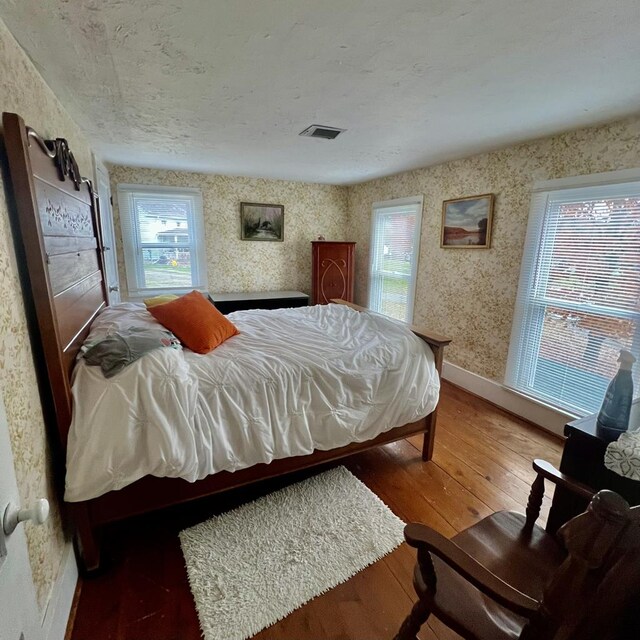 bedroom with dark hardwood / wood-style flooring and multiple windows