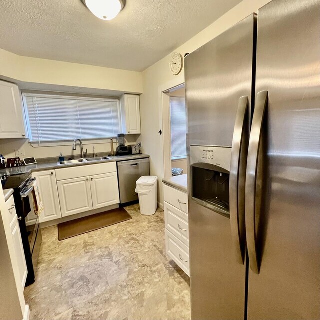 kitchen with a textured ceiling, stainless steel appliances, white cabinetry, and sink