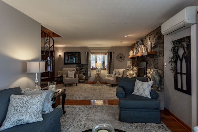 living room featuring hardwood / wood-style flooring, a stone fireplace, and a wall mounted AC