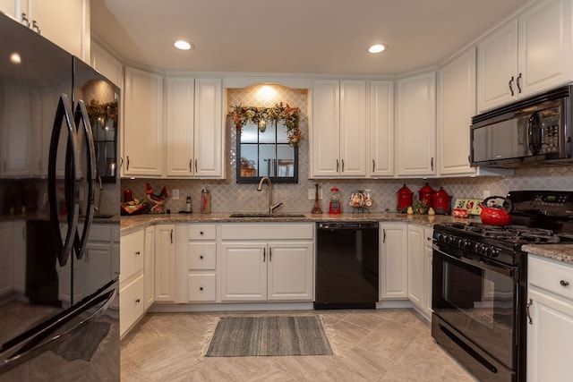 kitchen with sink, light stone counters, tasteful backsplash, black appliances, and white cabinets