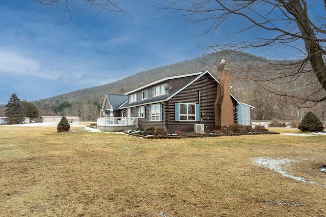 view of side of property featuring a mountain view and a lawn