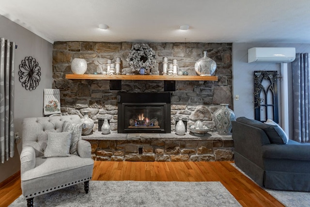 living room featuring hardwood / wood-style flooring, a wall mounted air conditioner, and a fireplace