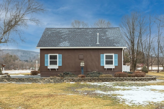 view of snowy exterior with a mountain view and a lawn