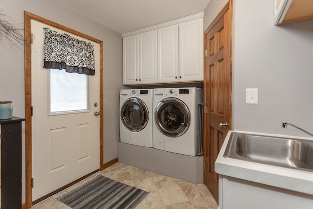 clothes washing area featuring cabinets, sink, and washing machine and dryer