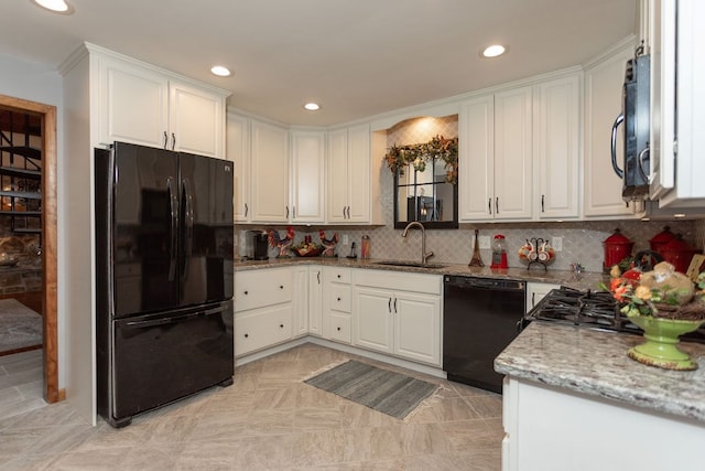 kitchen with tasteful backsplash, sink, white cabinets, black appliances, and light stone countertops