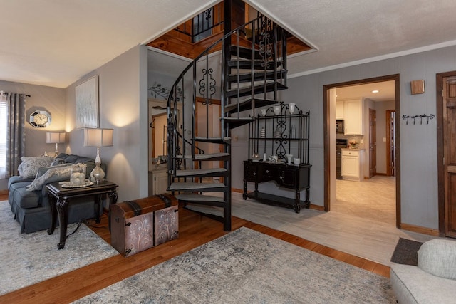 stairs with ornamental molding and hardwood / wood-style floors