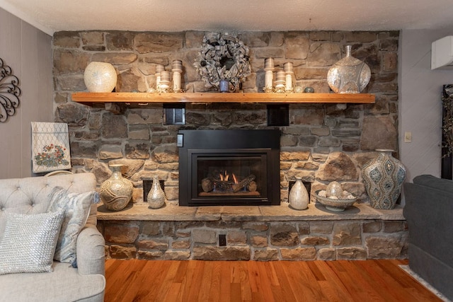 interior details featuring wood-type flooring, a stone fireplace, and a textured ceiling