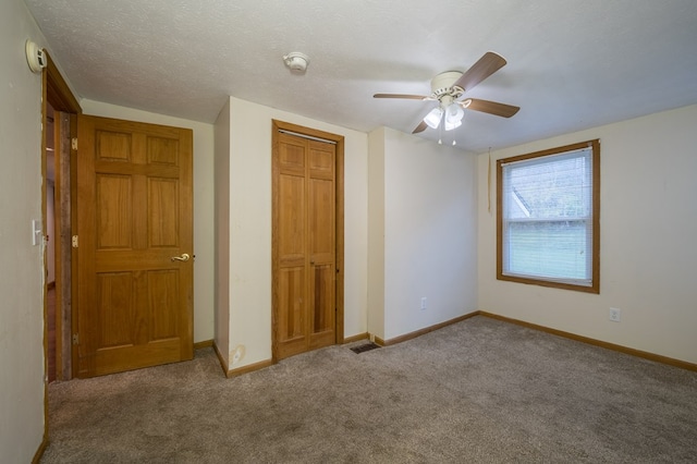 unfurnished bedroom with ceiling fan, a closet, light colored carpet, and a textured ceiling